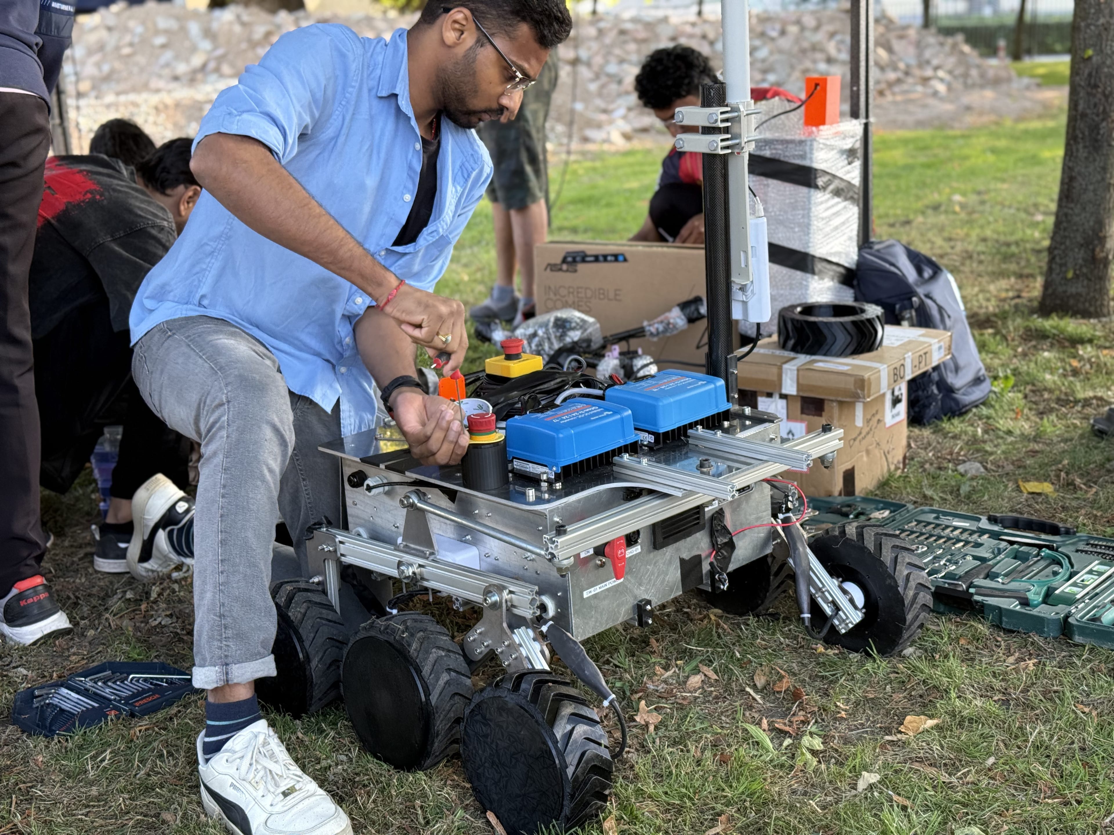 The rebuild continues on the grass with the tool kit and spare wheels laid out around the chassis.