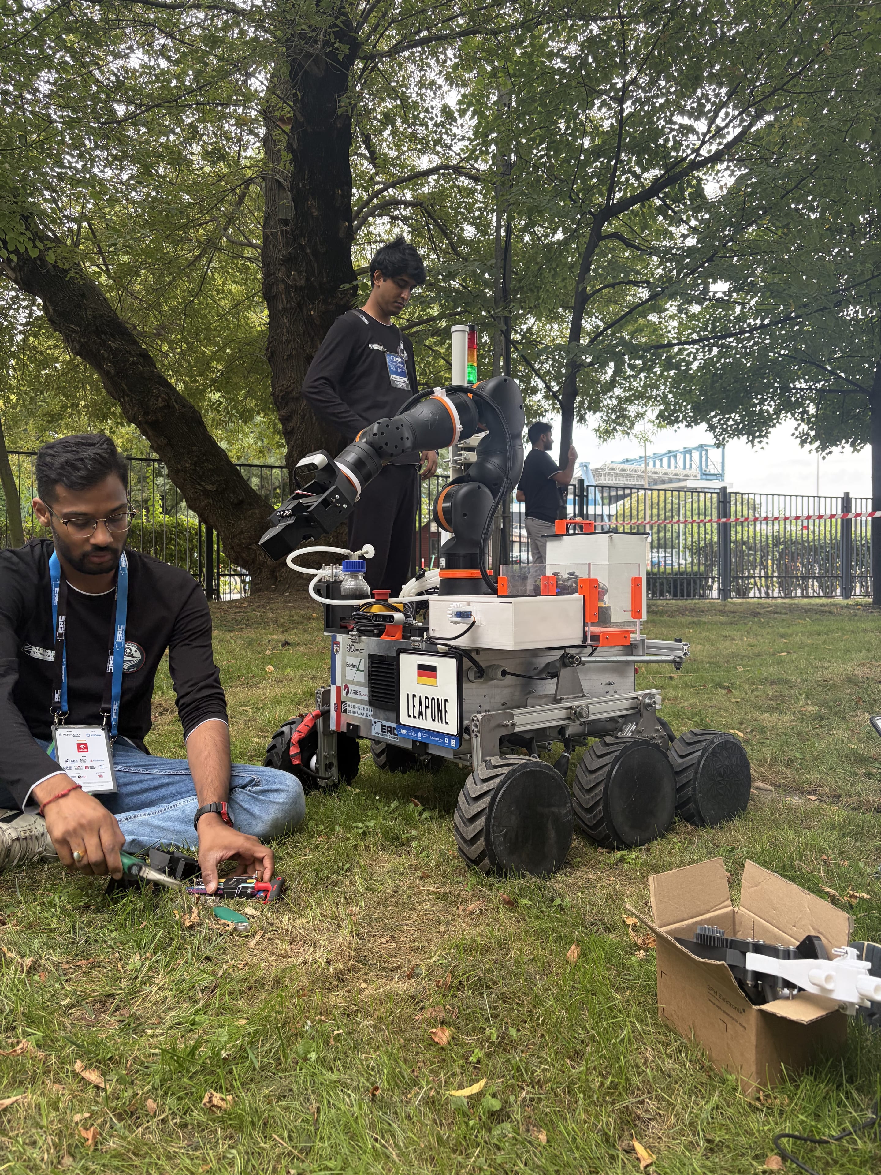 One team member sets the arm while another sorts tools on the lawn before a run.