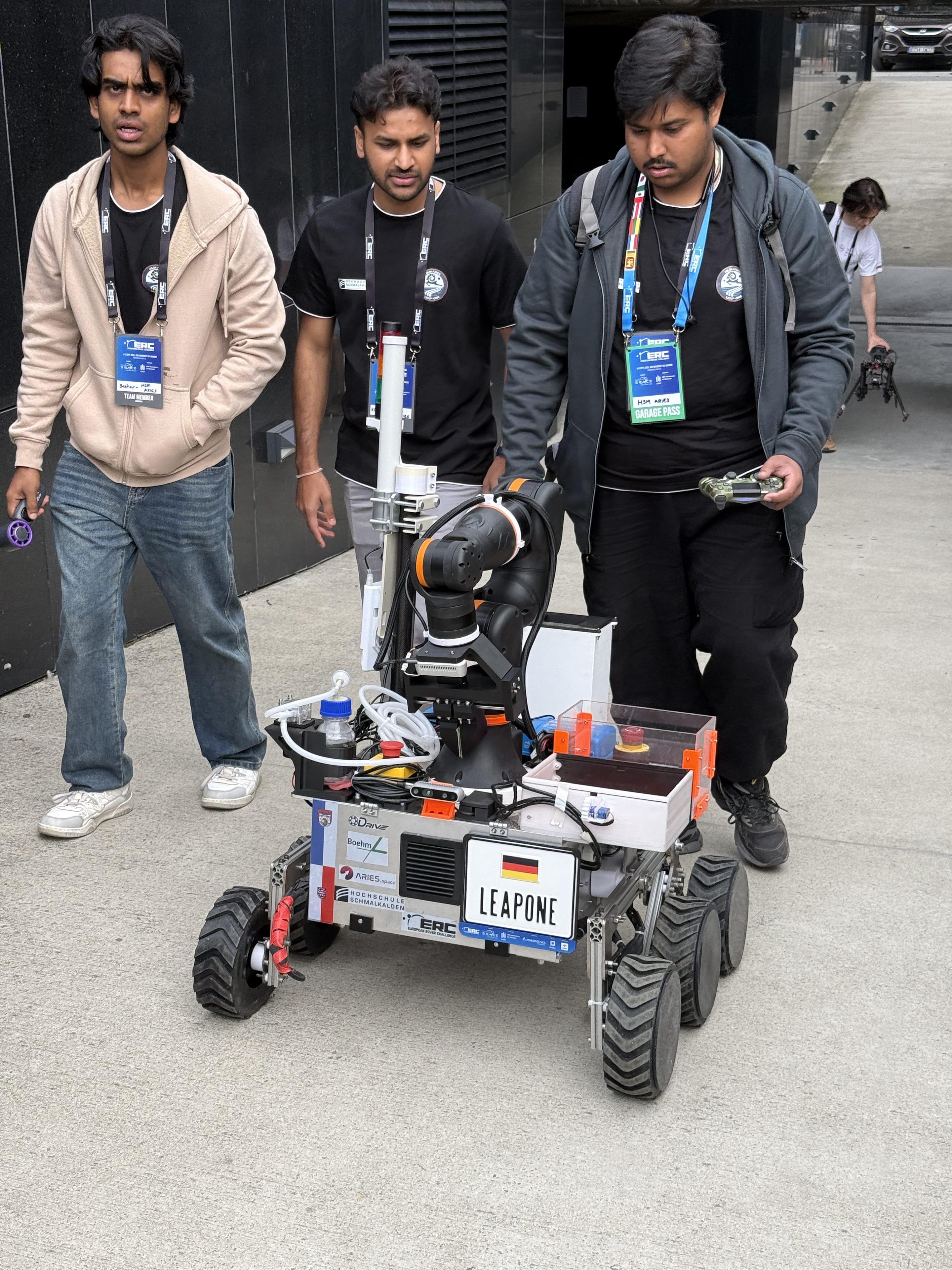 Three team members walk LEAP-One out to the field with the controller in hand.