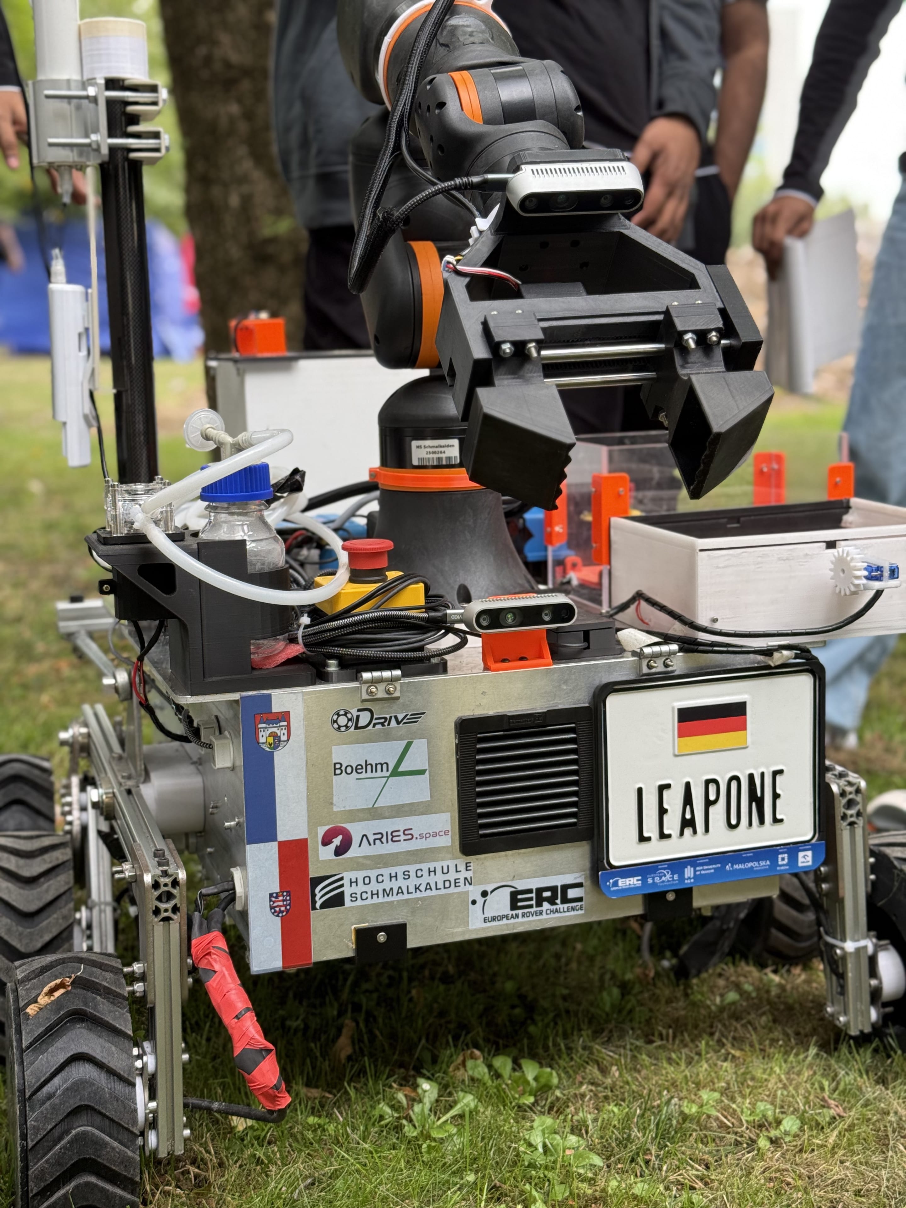 The gripper, depth camera and emergency stop sit above the sponsor logos on LEAP-One's front.