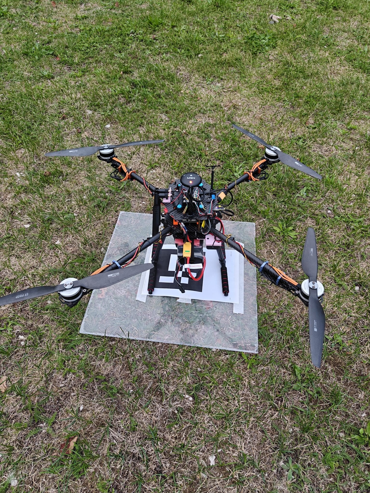 The carbon quadcopter sits on its printed marker sheet seen from above.
