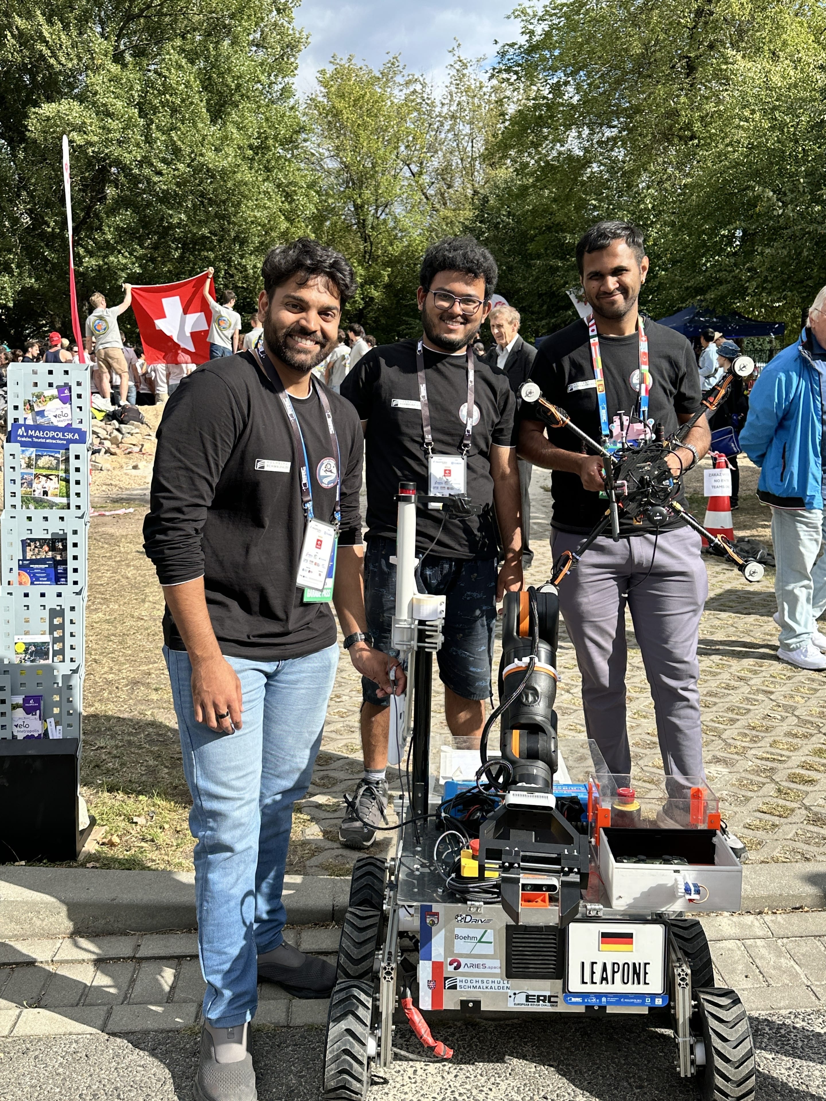 Three team members stand behind LEAP-One with the quadcopter in hand.