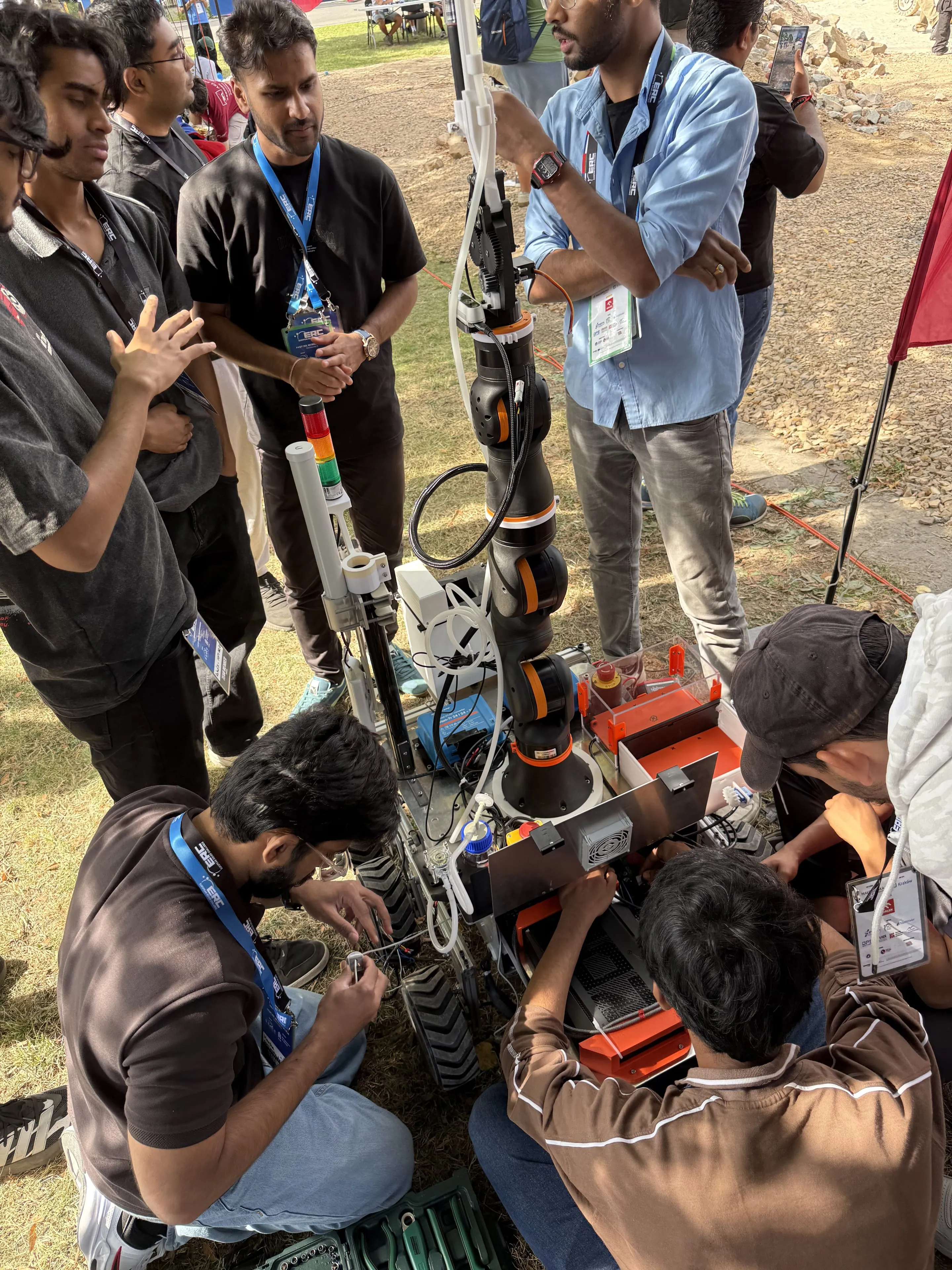 Team members repair wiring beside LEAP-One’s arm and signal tower in the pit at ERC 2026