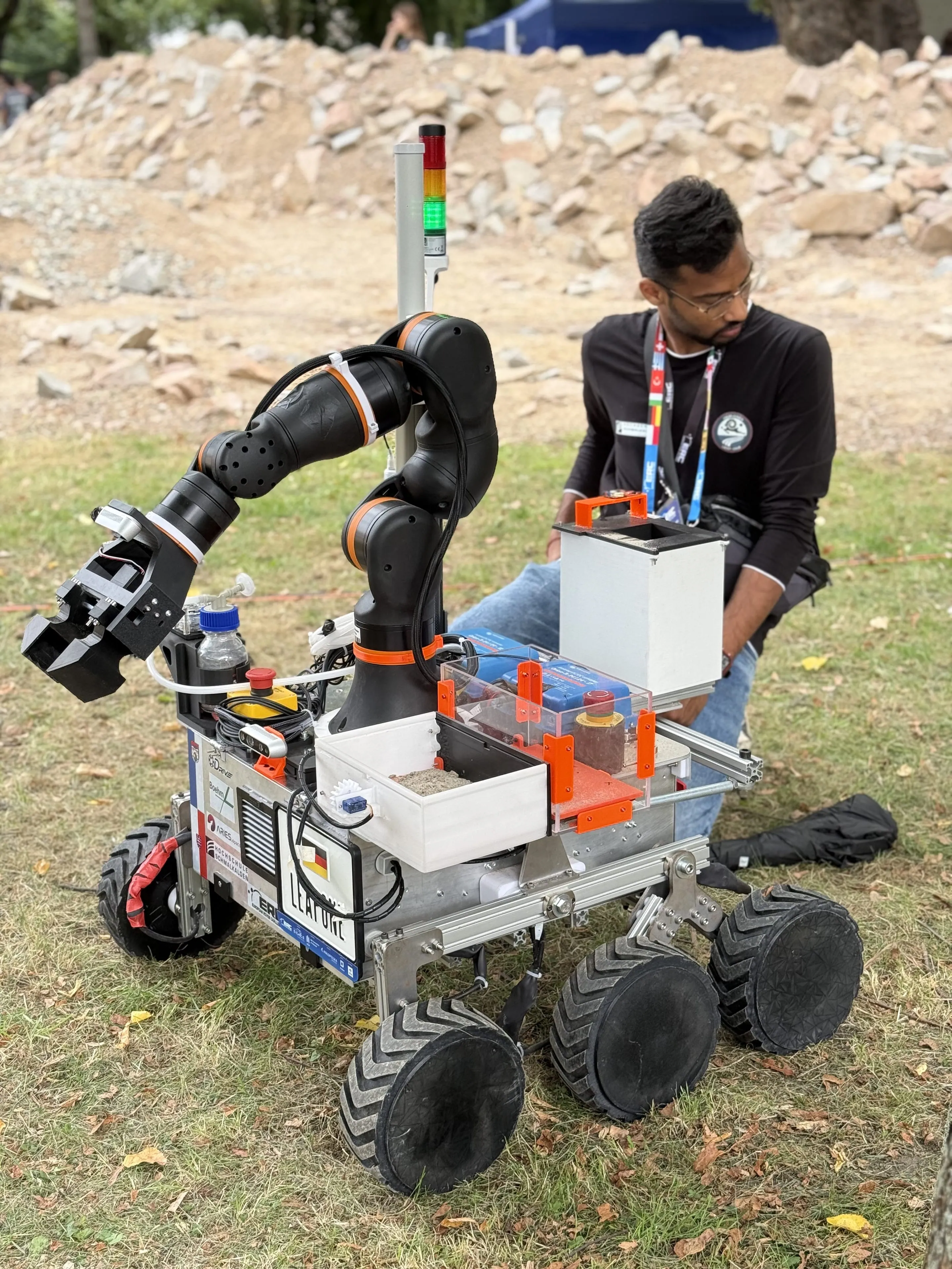 A team member kneels beside LEAP-One with sample containers mounted and the arm raised.